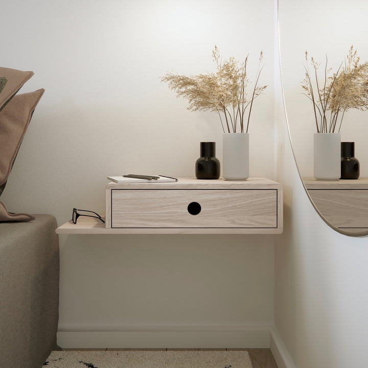 Wall mounted nightstand with a sleek black design, drawer slightly open revealing wooden interior