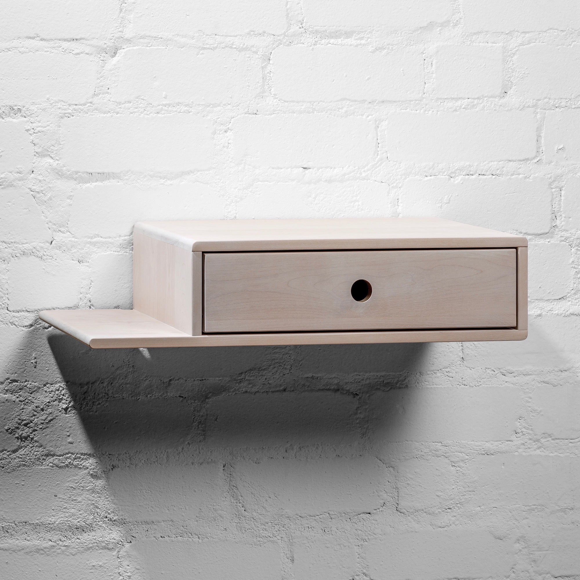 Bedside table featuring a white wooden finish and minimalist handle-free drawer design
