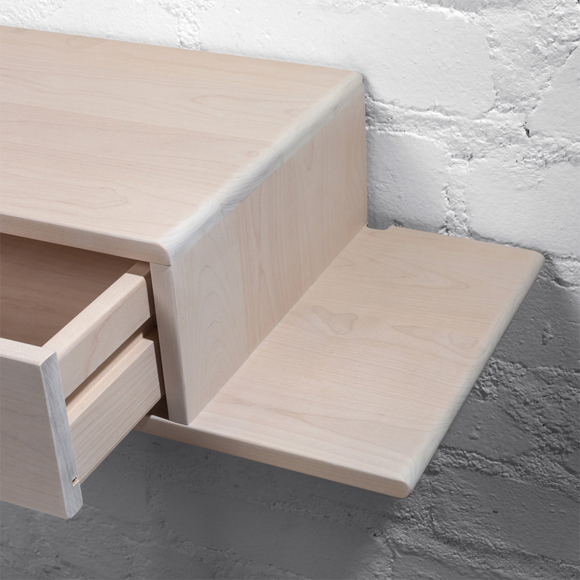 Solid wood nightstand mounted on a textured brick wall, highlighting natural grain and durability
