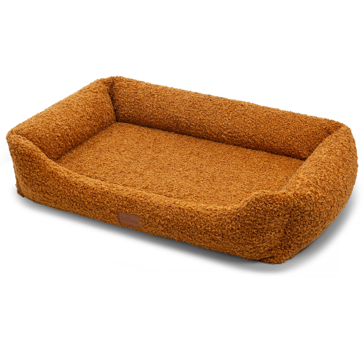 A rectangular pet bed with a high, rounded border, upholstered in a textured, sherpa-like bouclé fabric in a warm caramel-brown color. A small brown leather brand patch is visible on the front side.
