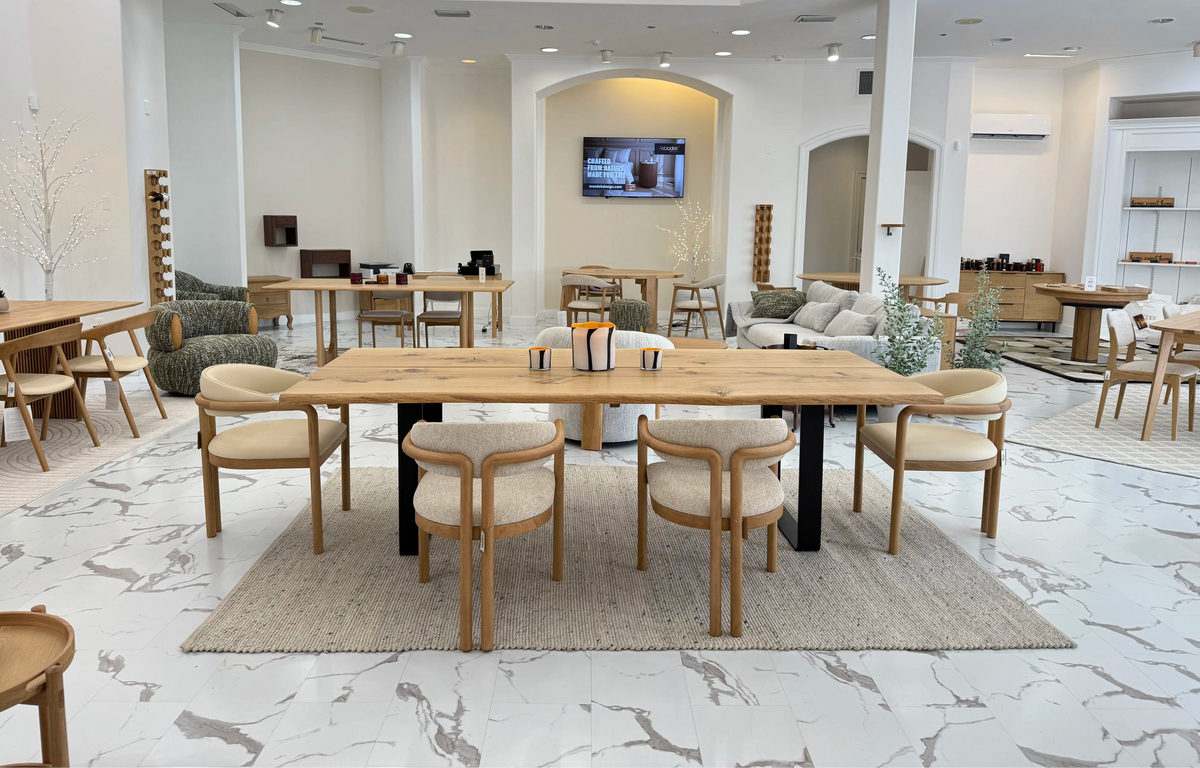 Light-filled showroom with natural oak tables, diverse seating styles, and beige woven rug on marble-effect flooring IMG_8449.webp gallery 1