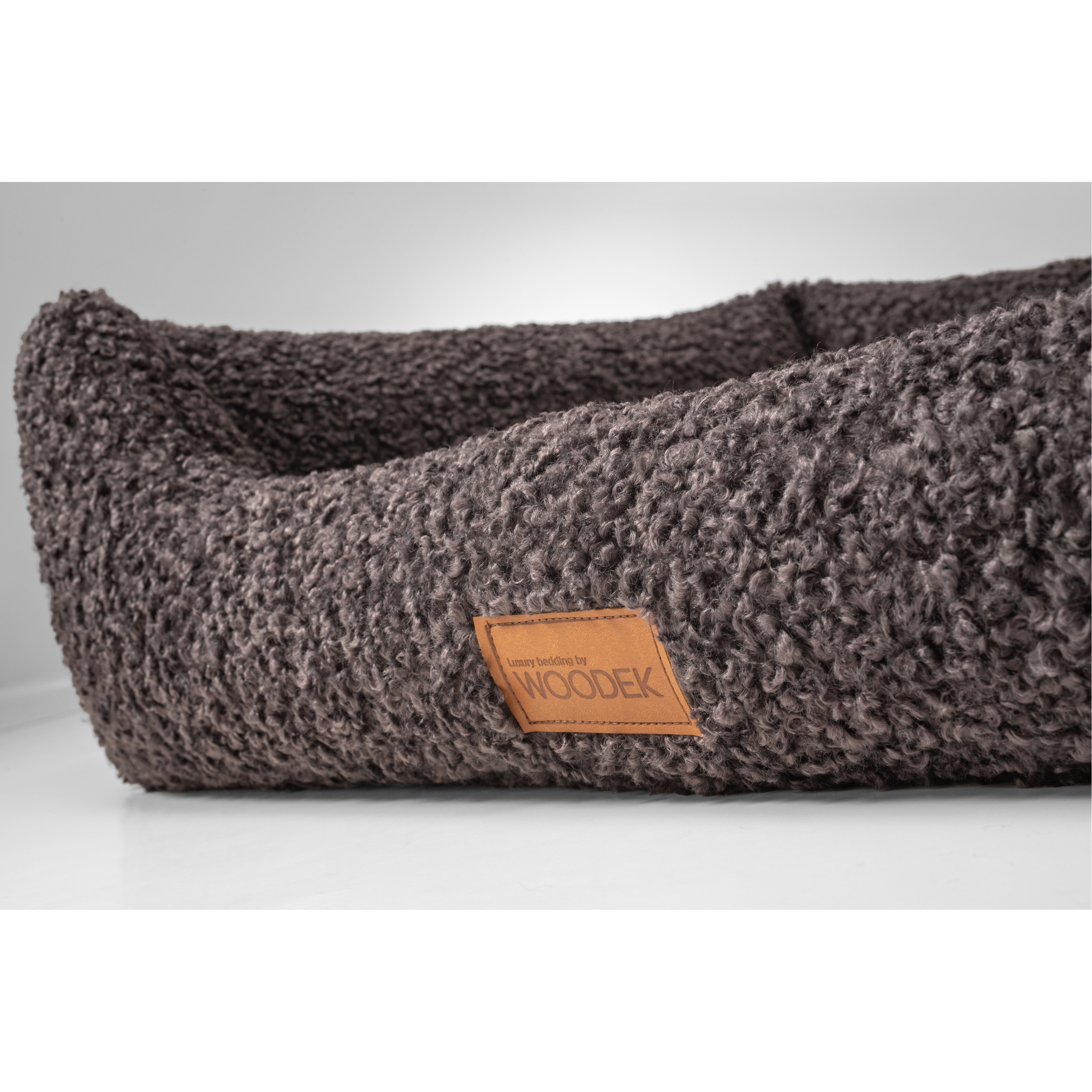 Close-up of the bolstered edge on a gray orthopedic dog sofa, providing comfort and ergonomic support for dogs