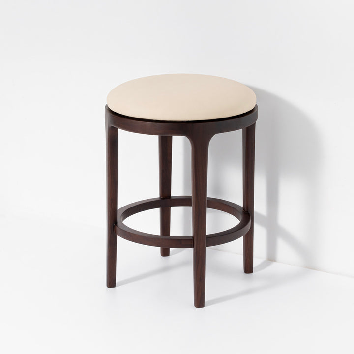 A modern bar stool with a dark brown wooden frame and a round light beige upholstered seat, shown against a clean white background.