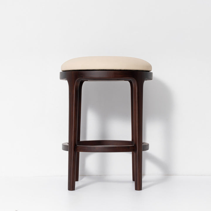 A modern bar stool with a dark brown wooden frame and a light beige upholstered seat cushion, shown against a plain white studio background.