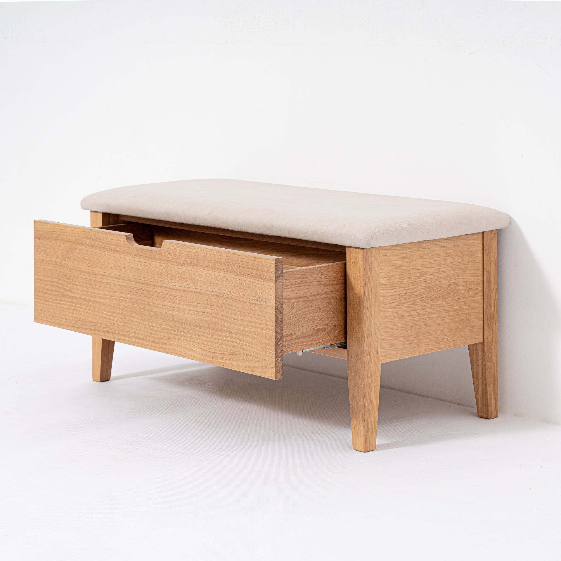 Wooden bench with a cream cushion and open drawer on a white background