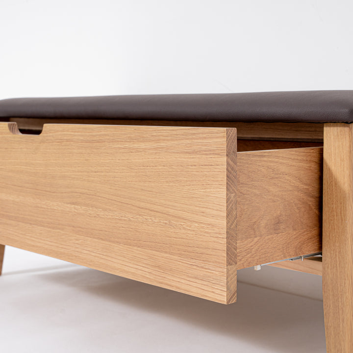 Wooden bench with a dark cushion top on a light background