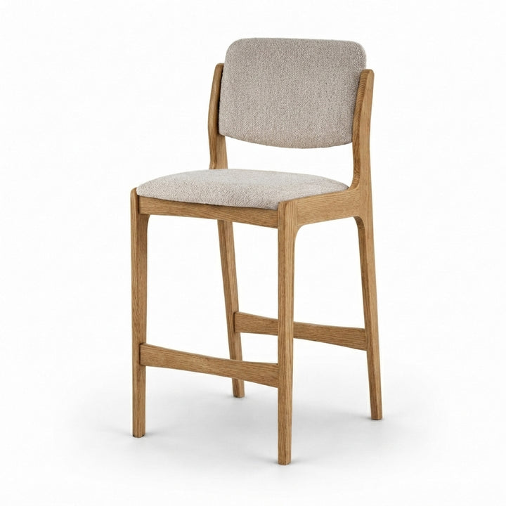 A modern bar stool with a light oak wood frame and a light beige textured fabric seat and backrest, shown on a clean white background.