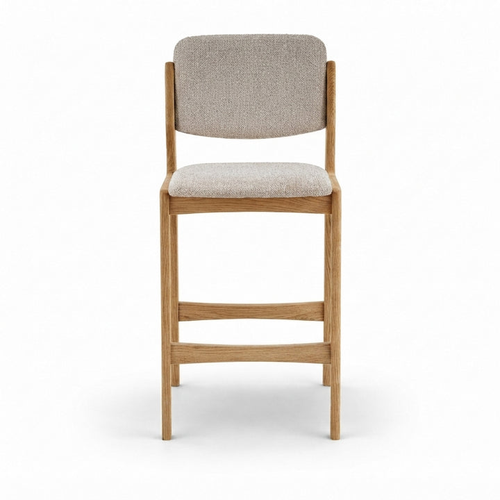 A modern counter stool with a light oak wood frame and light beige textured fabric upholstery on the seat and backrest, shown from a front-facing perspective on a white background.
