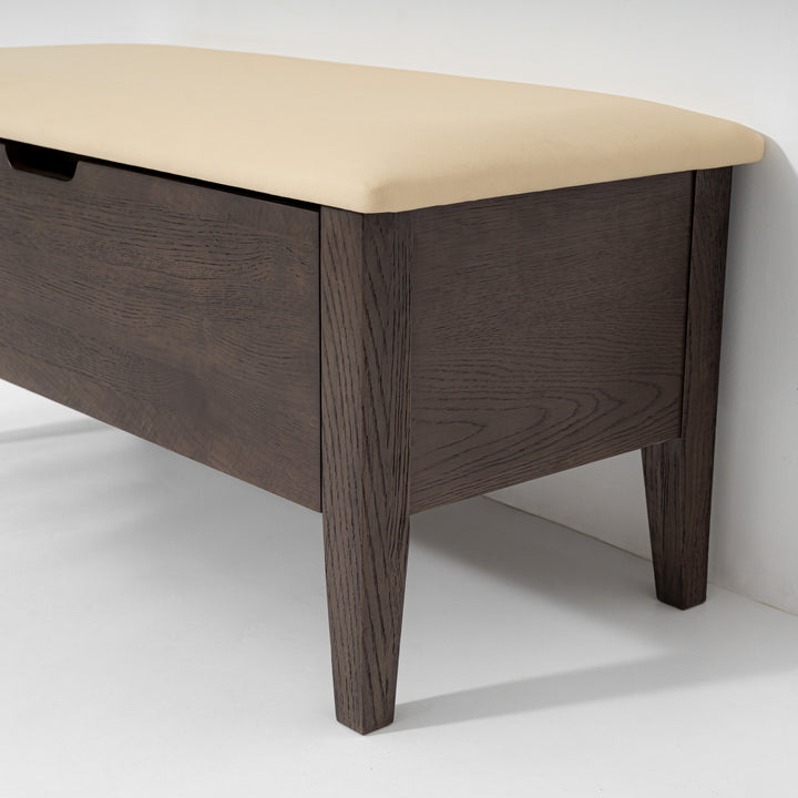 A dark brown wooden bench with a beige upholstered top and a hidden storage drawer on the left side, shown against a plain white background.