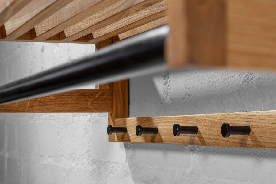 Scandinavian-style oak coat rack with decorative and functional elements, featuring neatly hung clothes and accessories