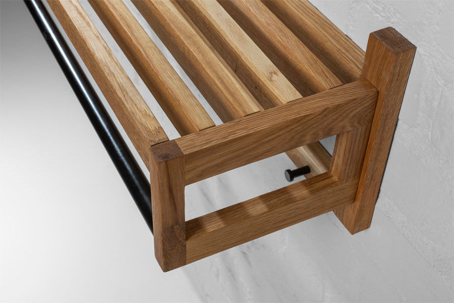Wall-mounted coat rack made of oak with hooks, shelf, and hanging rod, styled with personal accessories