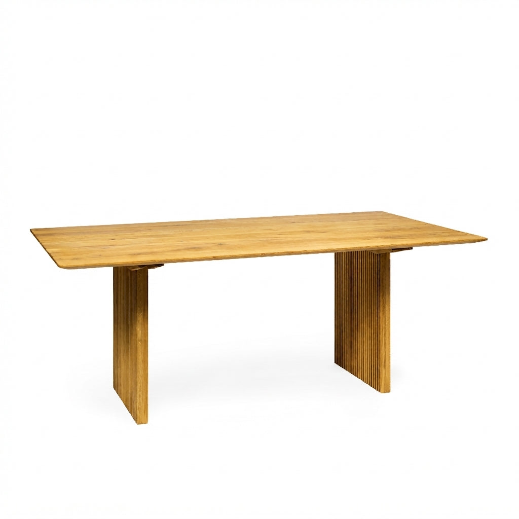 A rectangular wooden dining table with a light oak finish, featuring a thick top and two blocky pedestal legs, shown on a plain white background.