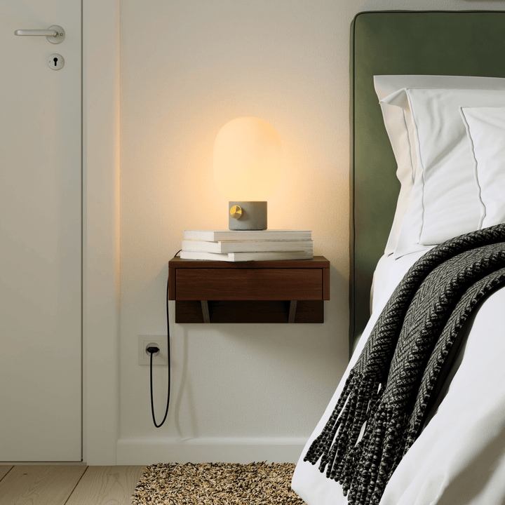 A modern, wall-mounted wooden floating nightstand in a rich brown finish, perfect for minimalist bedroom decor