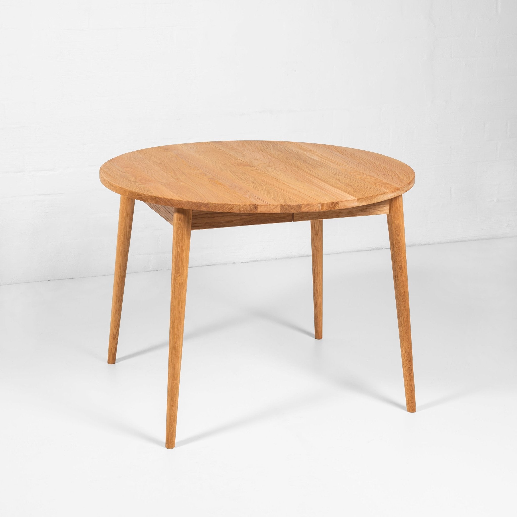 Handcrafted circular oak dining table with extension feature and rustic grain details