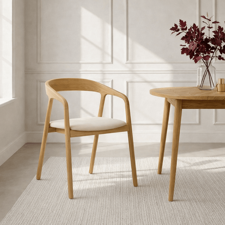 Celeste Oak Dining Chair lifestyle view in a Scandinavian dining room with natural oak frame and smooth beige leather seat