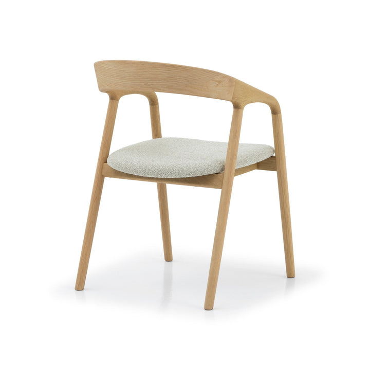 Celeste Oak Dining Chair angled front view showing sculpted oak armrest rail, open backrest curve, and off-white Cloud seat