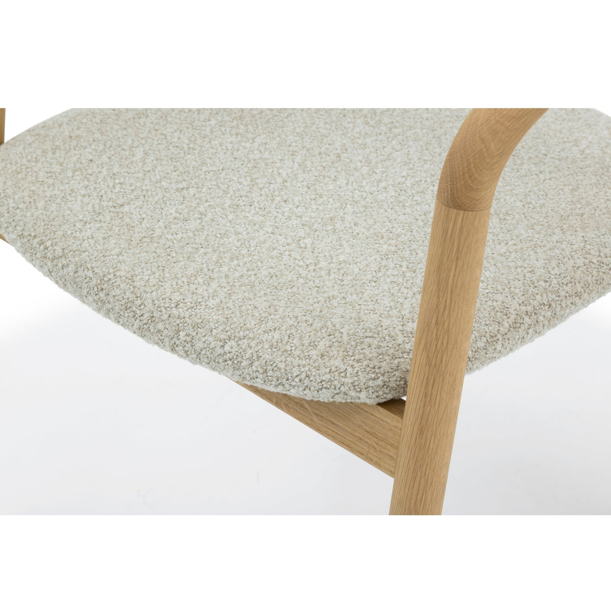 Macro close-up of Celeste Oak Dining Chair seat area showing off-white Cloud boucle fabric texture and solid oak armrest rail