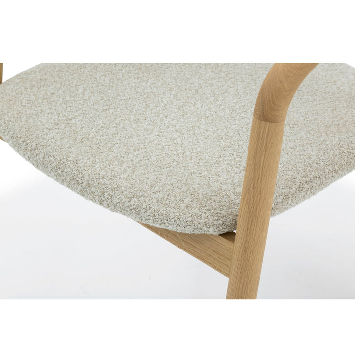 Macro close-up of Celeste Oak Dining Chair seat area showing off-white Cloud boucle fabric texture and solid oak armrest rail