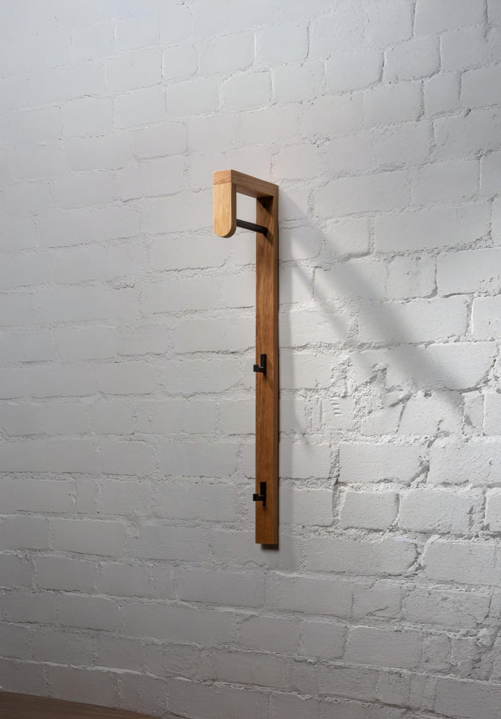 Vertical oak coat rack with metal hooks and minimalist frame for entryway storage
