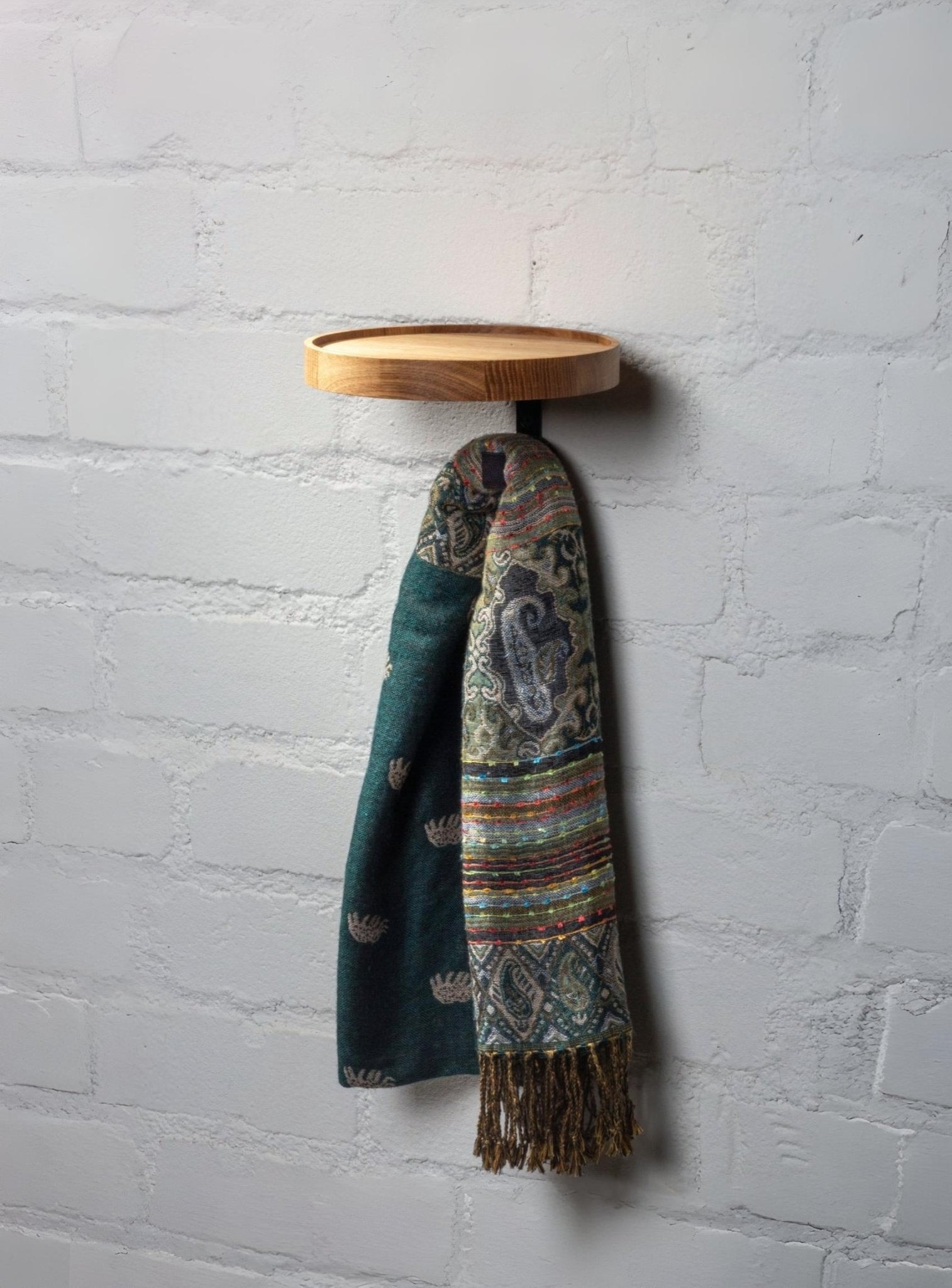 Minimalist oak coat rack with one hook and small circular storage tray for entryway