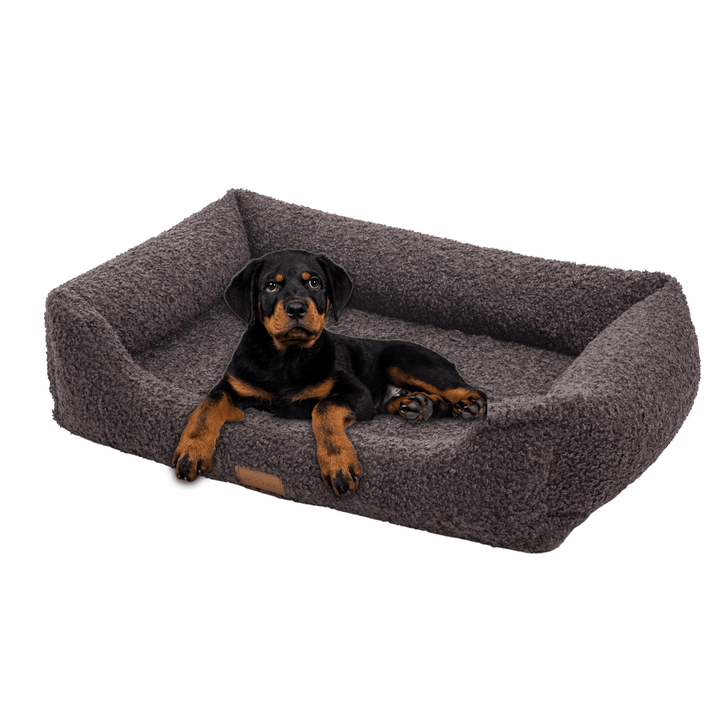 Black and tan puppy resting on a gray orthopedic dog bed, designed for ultimate comfort and support for joints.