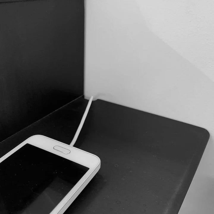 Hope Floating Nightstand Black Beech -close-up of surface with smartphone and charging cable, solid black beech corner detail