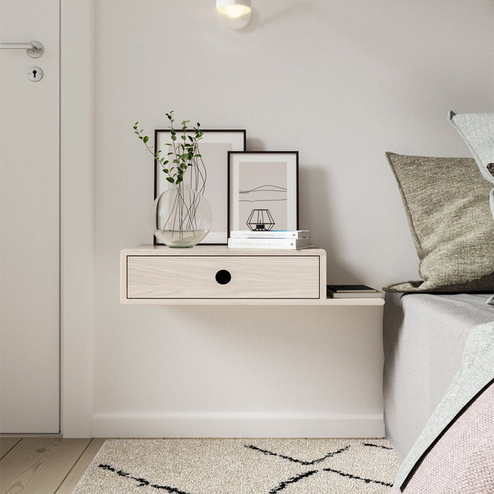 Floating nightstand mounted on a white wall, featuring a single drawer with a minimalist black finish