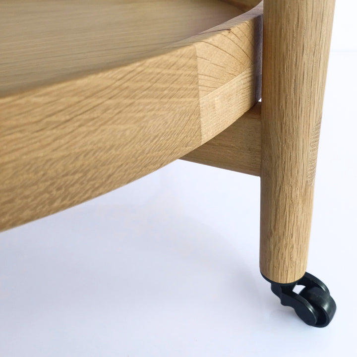Wooden Serving Table Hugo - Oak close-up on the leg with black caster wheel and natural solid oak round tray detail in minimalist Scandinavian design