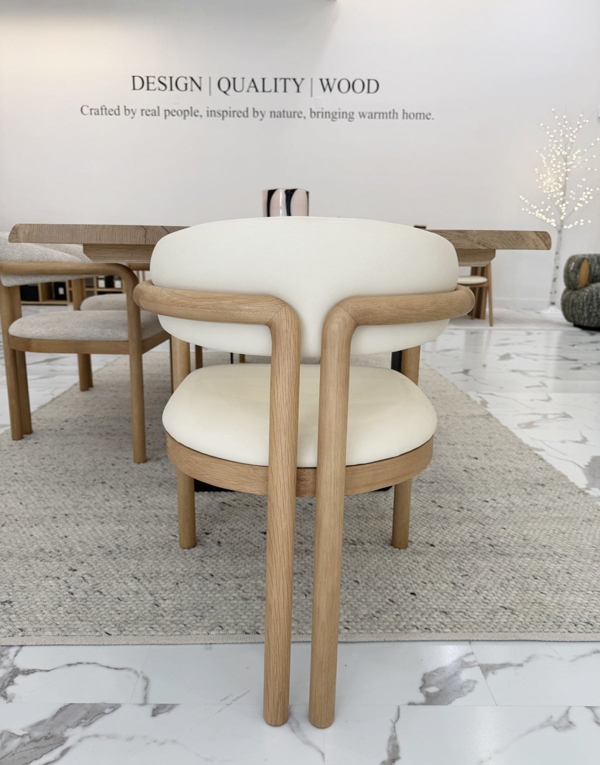Nature Oak Dining Chair rear view in a Woodek Design showroom beside a solid oak dining table with multiple chairs around it