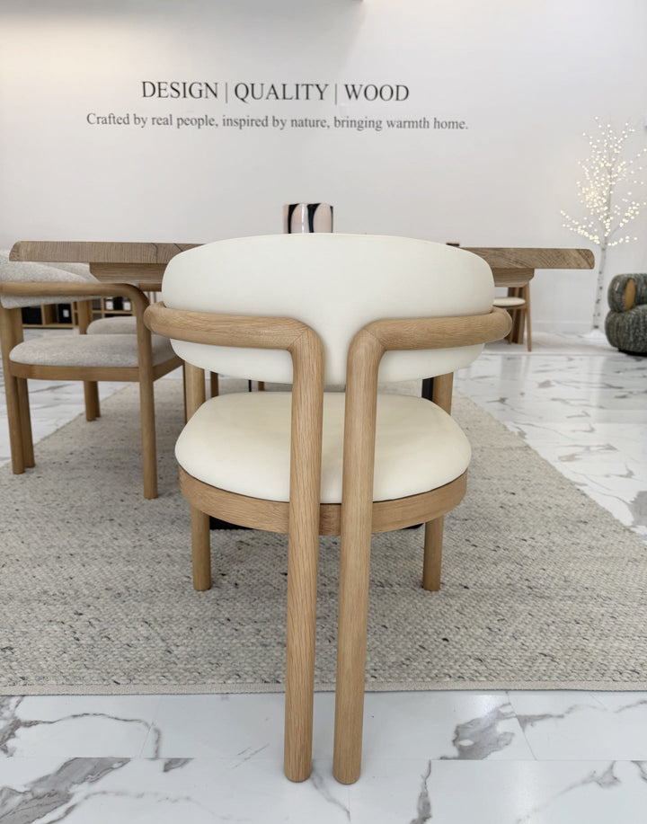 Nature Oak Dining Chair rear view in a Woodek Design showroom beside a solid oak dining table with multiple chairs around it