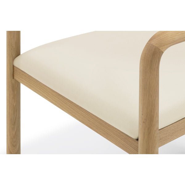 Macro closeup of Nature Oak Dining Chair showing beige leather seat surface, solid oak armrest rail, and rounded frame detail