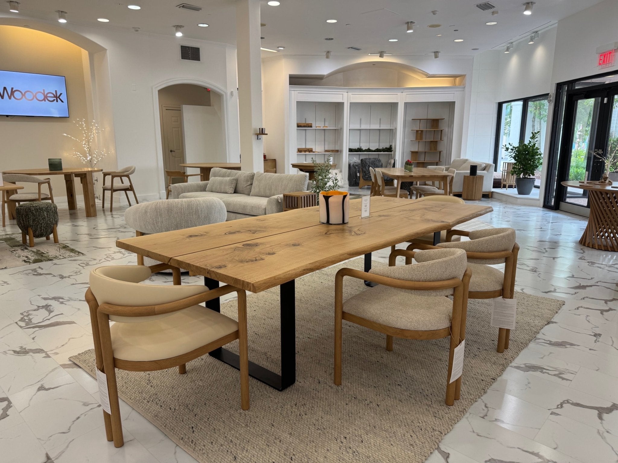 Multiple Nature Oak Dining Chairs around a large solid oak dining table in the Woodek showroom with warm natural lighting