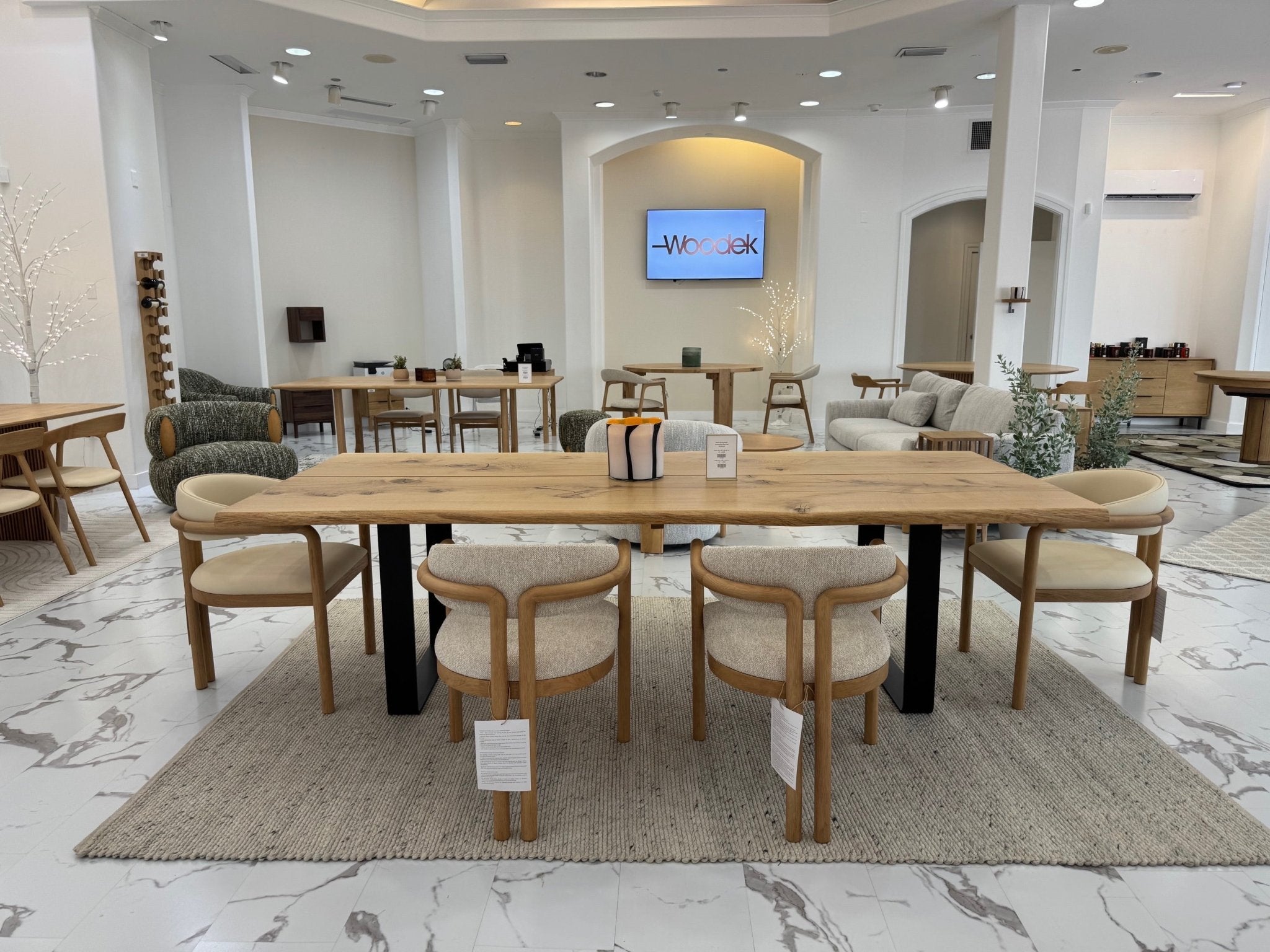 Nature Oak Dining Chair rear view in a showroom setting showing curved oak backrest, rounded back panel, and leather seat cushion