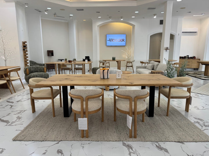 Nature Oak Dining Chair rear view in a showroom setting showing curved oak backrest, rounded back panel, and leather seat cushion