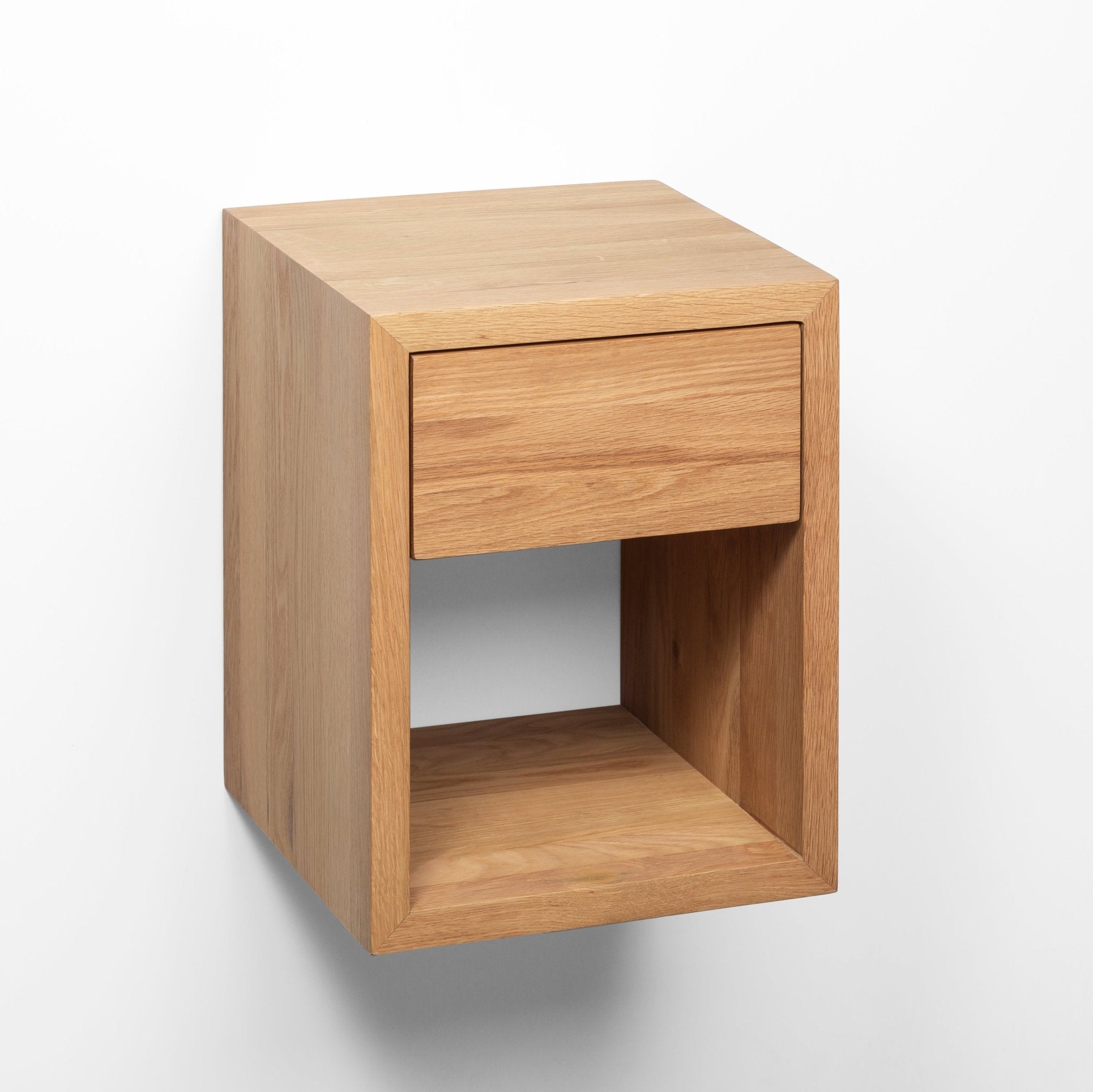 Small wall-mounted wooden bedside table with natural oak grain and seamless drawer