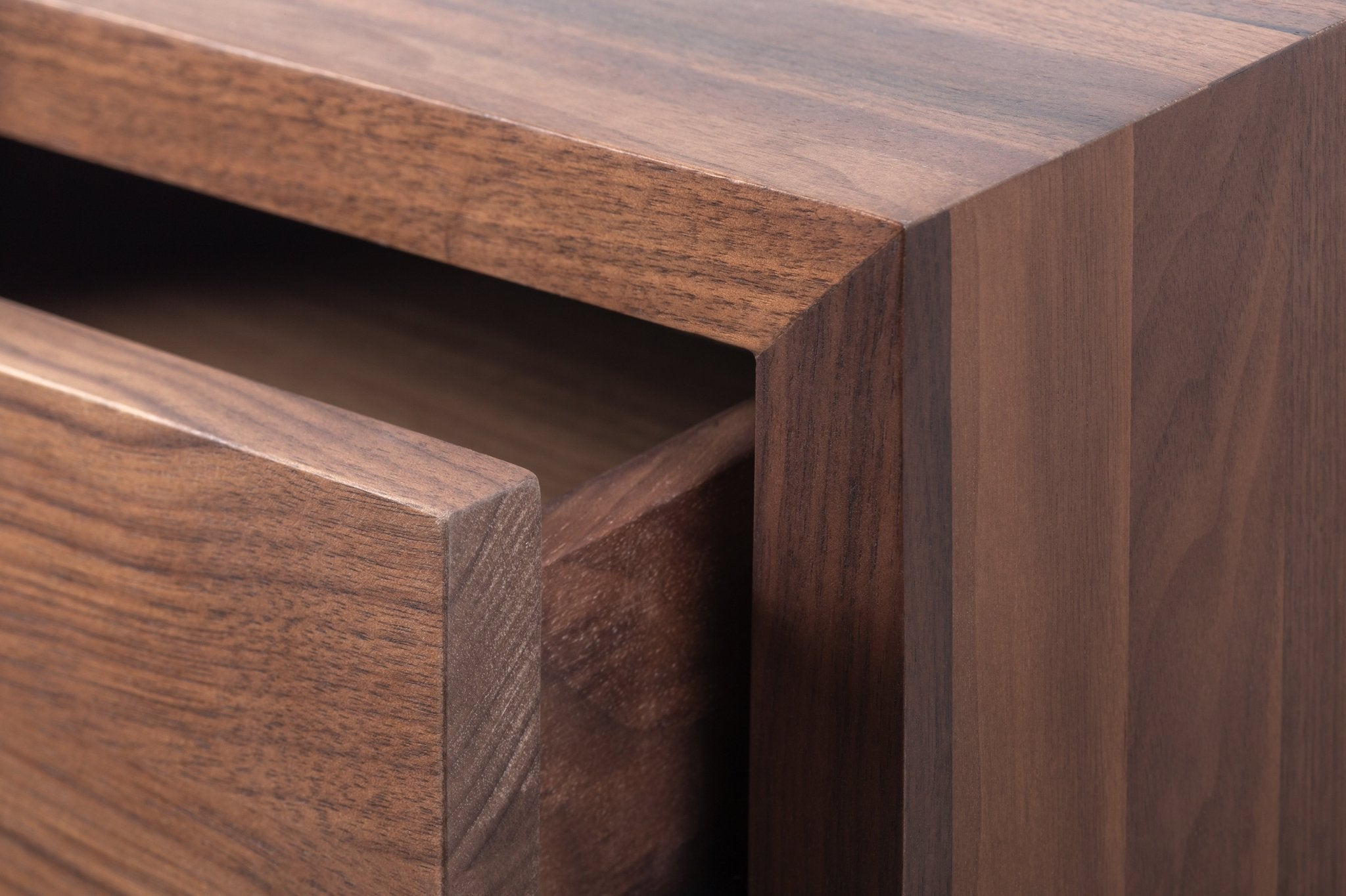 Macro close-up of Hugo Walnut Nightstand drawer edge showing deep walnut grain texture, push-to-open gap, and matte lacquer