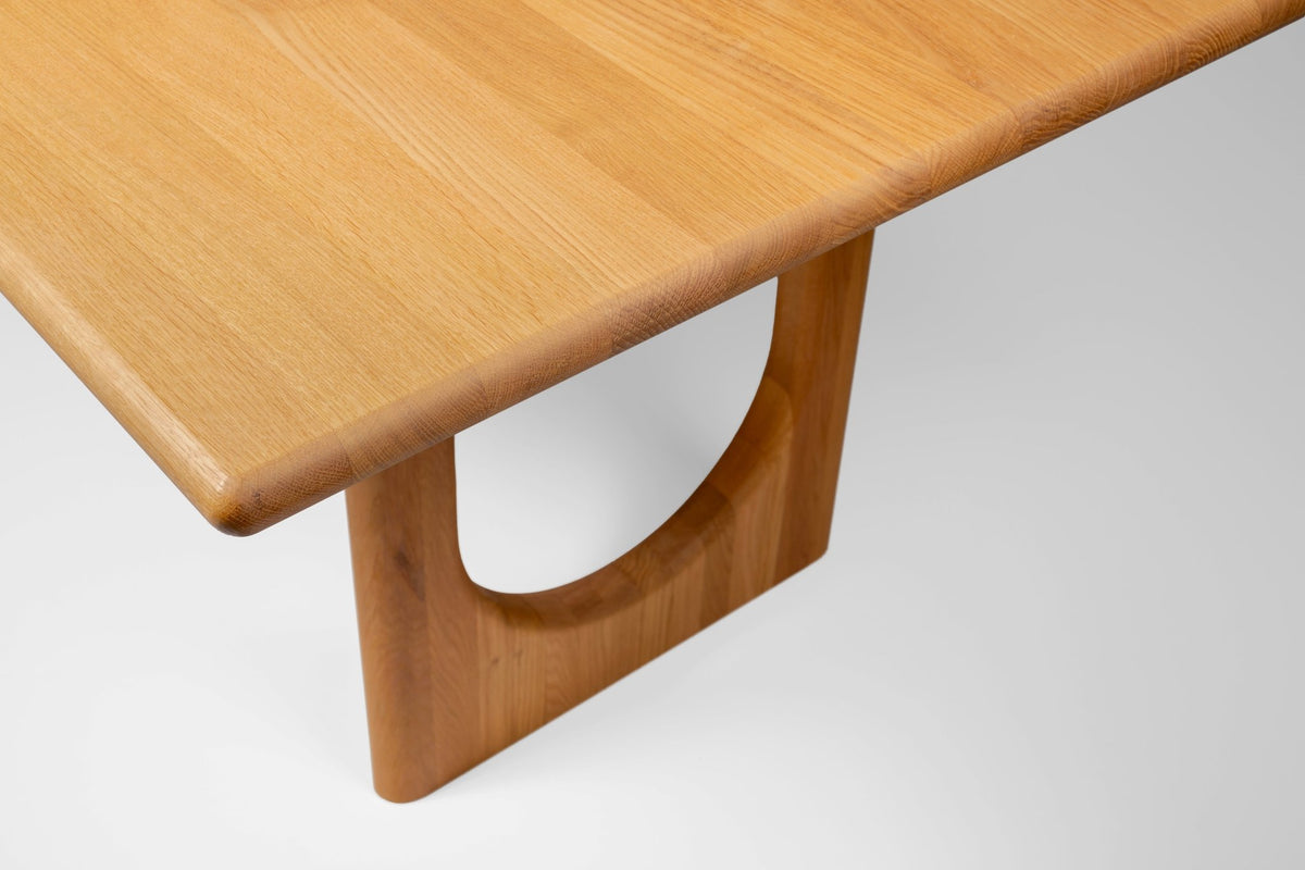 Close-up of the Theo dining table arched oak leg and rounded tabletop edge