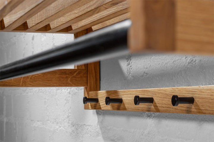 Scandinavian-style oak coat rack with decorative and functional elements, featuring neatly hung clothes and accessories
